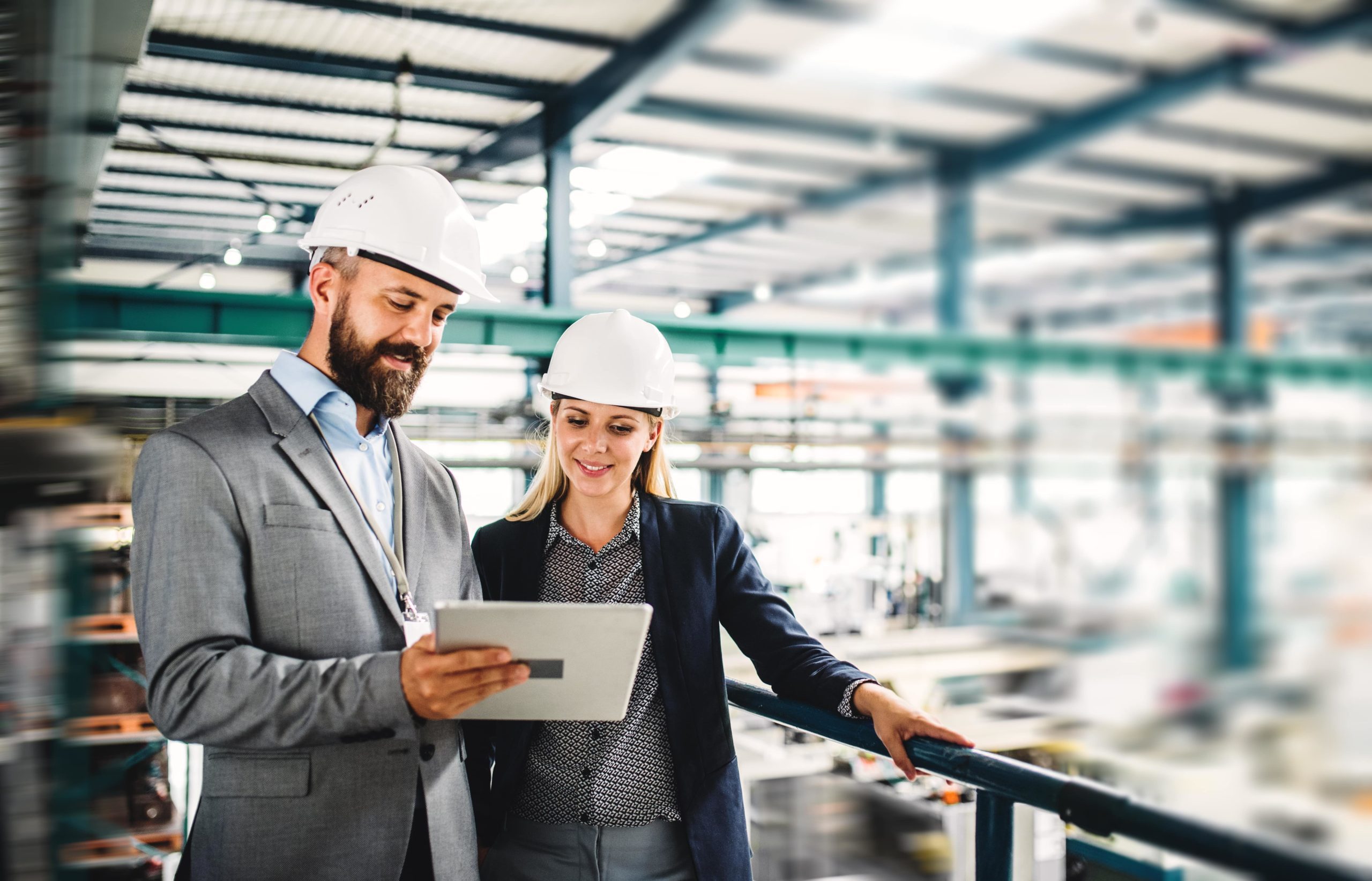 Mann und Frau in der Fabrik, die über Arbeitsschutz mit iPad in der Hand sprechen